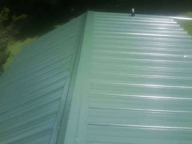 New green metal panels meeting at the ridge of a roof — Flat Roof Repair work by our crew in Beaumont