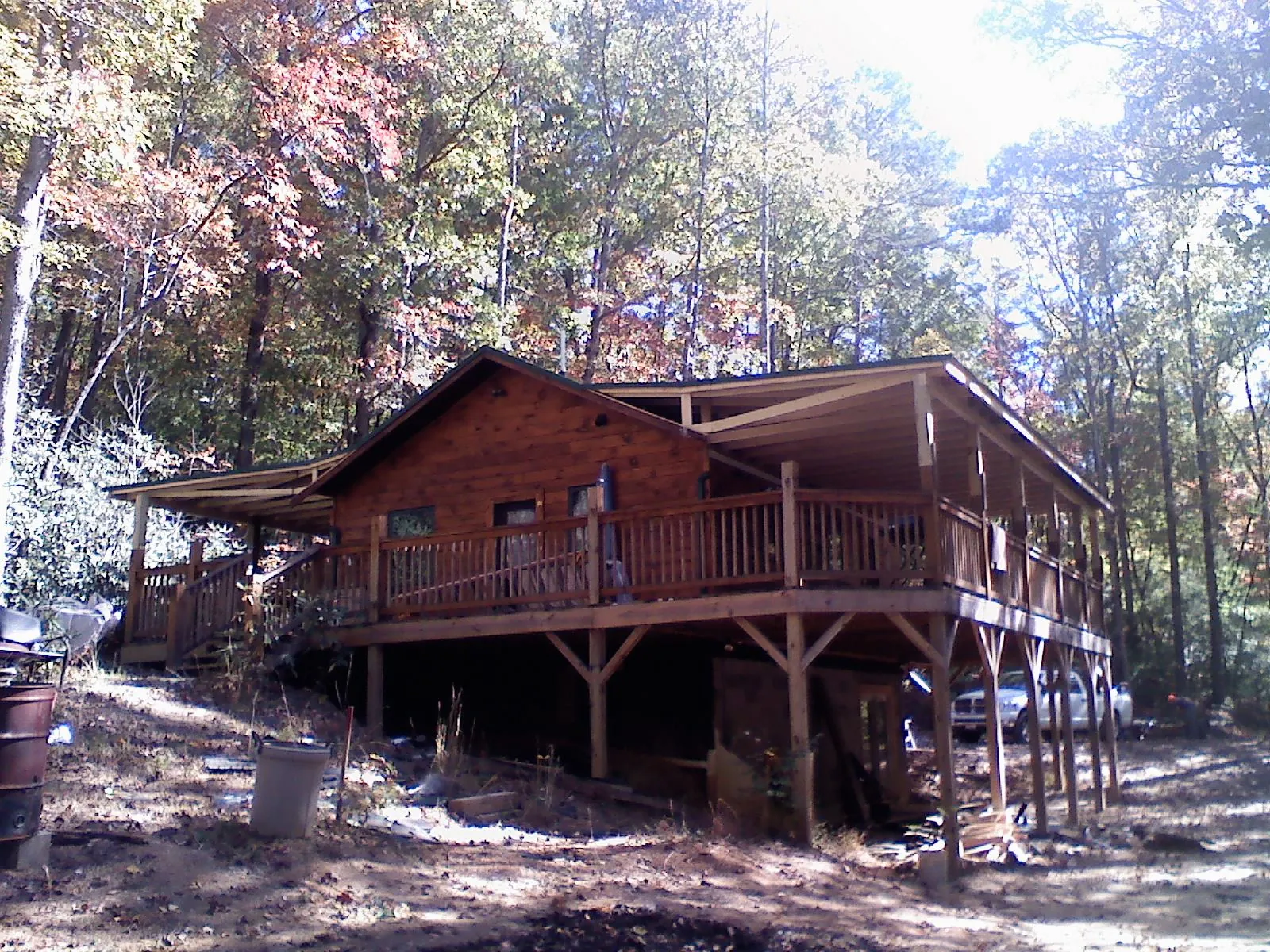 Log cabin with a wraparound porch and metal roof in the fall in Beaumont