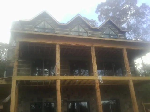 Dormers and porch framing on a large log home under construction — Roof Coating work by our crew in Beaumont