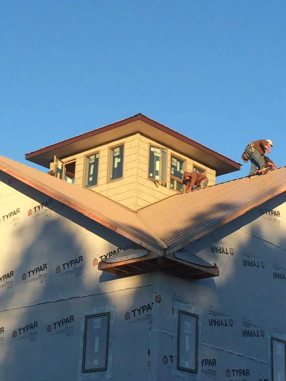 Roofers working around a rooftop cupola on a new metal roof at sunset — Roof Waterproofing in Beaumont by Roofing Brothers
